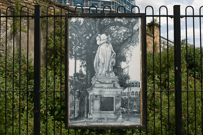 a billboard displays an intricate pencil drawing of a headless statue
