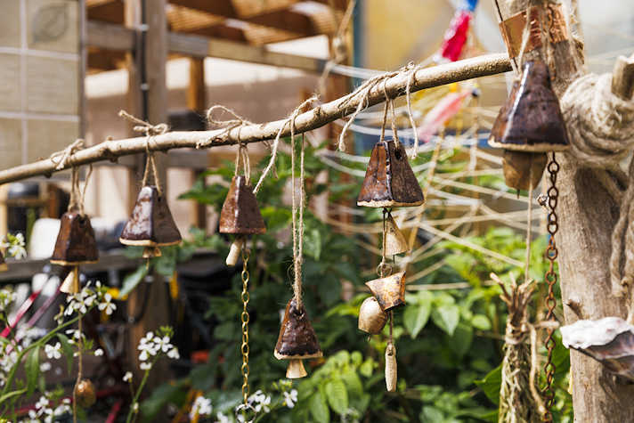 A close up of a string of bells that are hanging over green plants.