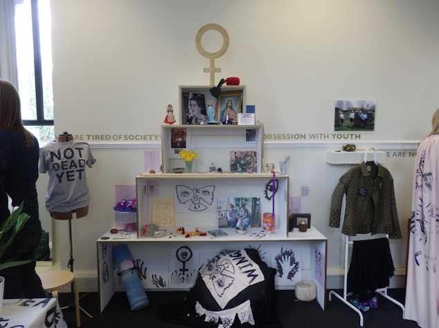 A shrine to death, with t-shirt reading "not dead yet", pictures of loved ones, feminist symbols and images of loved ones.