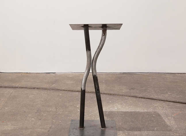 A lectern made from metal welded together stands in a white room.