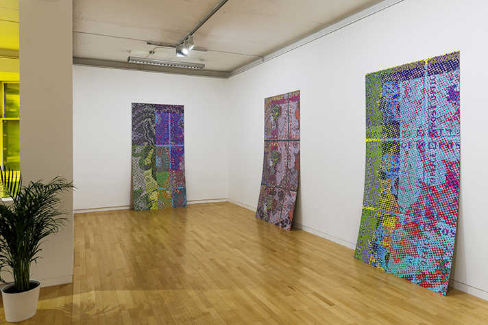 Three large printed artworks are displayed on a white wall.