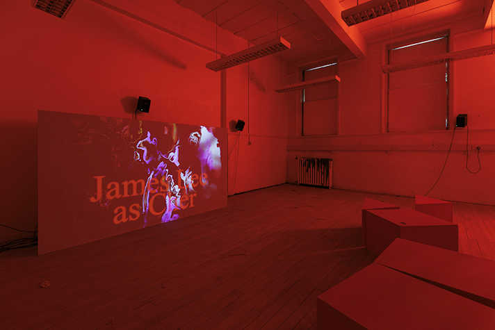 Film is projected onto a screen in a room lit in red.