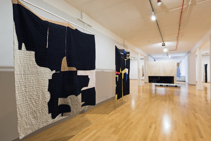 installation view image of large scale quilt hangings with abstract cut out shapes