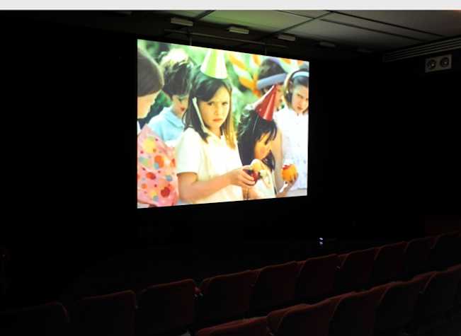projection screen in dark room with image of children in party hats